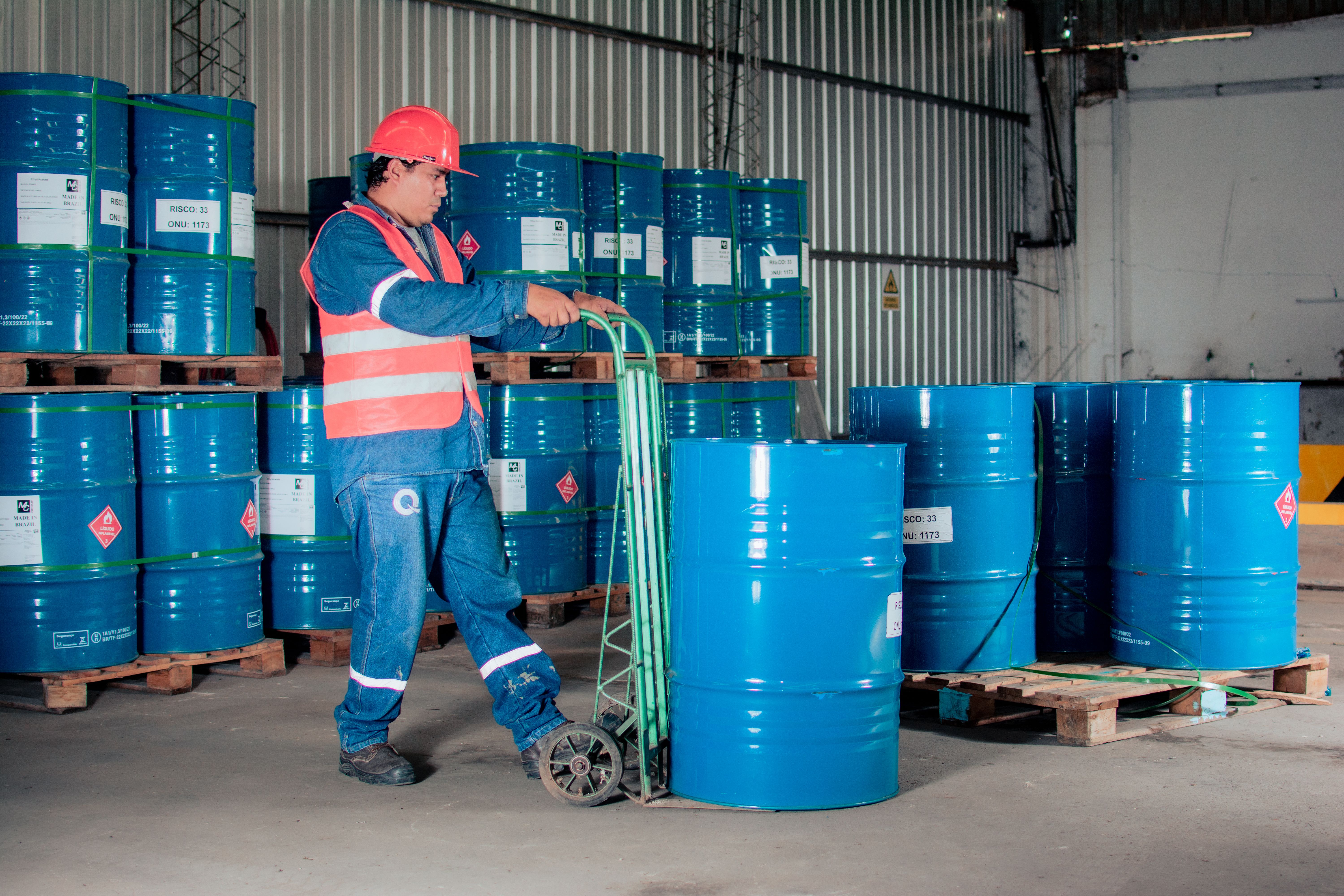 Trabajador con equipo de proteccion transportando barriles